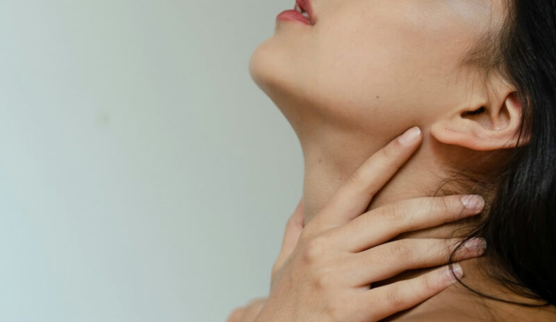 喉を押さえる女性