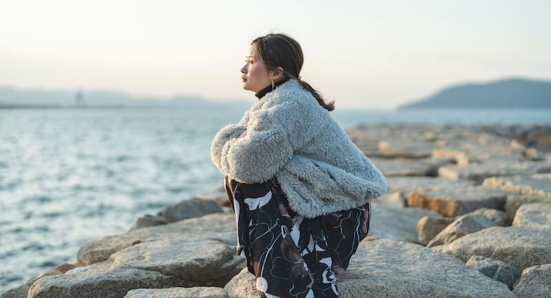 冬の夕暮れの海にいる女性